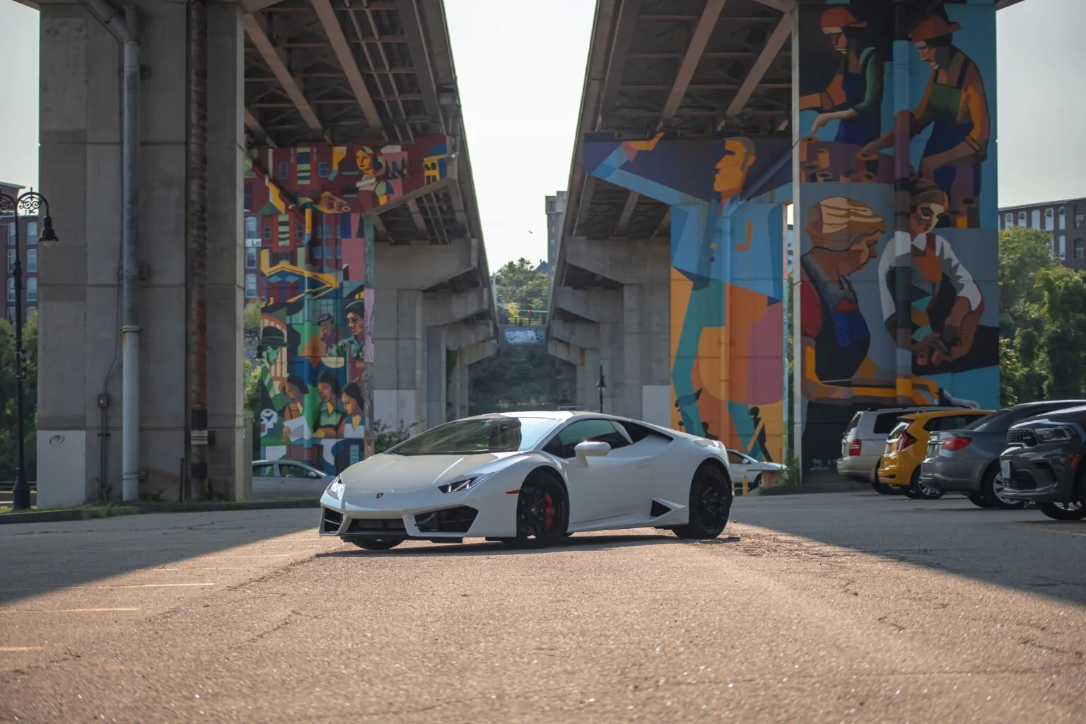 White Lamborghini Huracán beneath a colorful city bridge